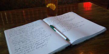 An open notebook with handwritten notes and a pen