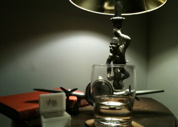 A bedside lamp and nightstand in a dark bedroom