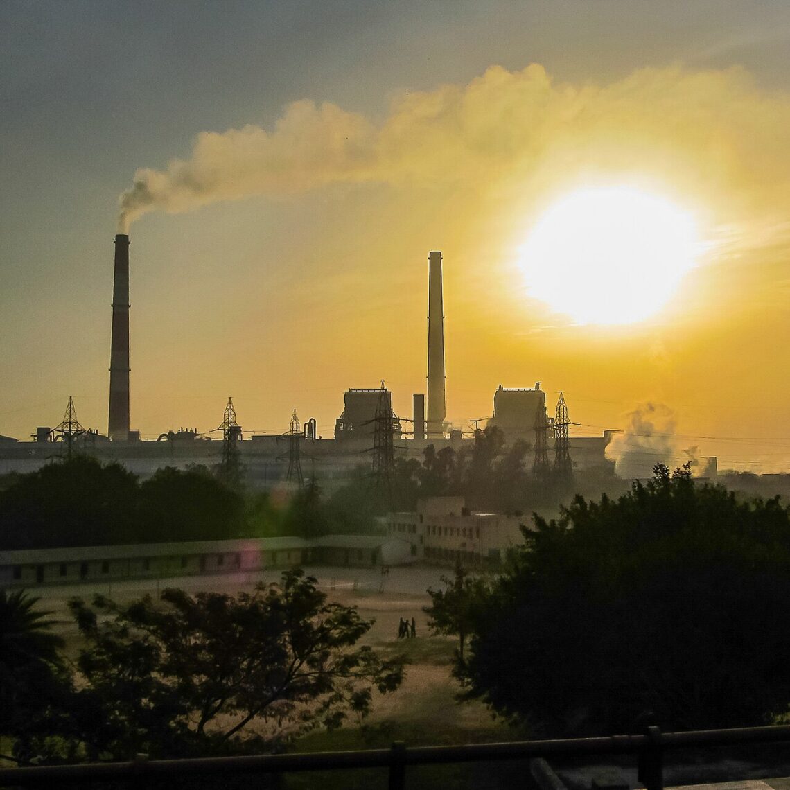 Air Pollution and Health: How to Stay Safe on High AQI Days Hazy sunrise over Delhi with smoke from a power plant clouding the sky