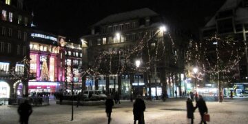 Wooden stalls and Christmas lights at a busy European Christmas market in the evening