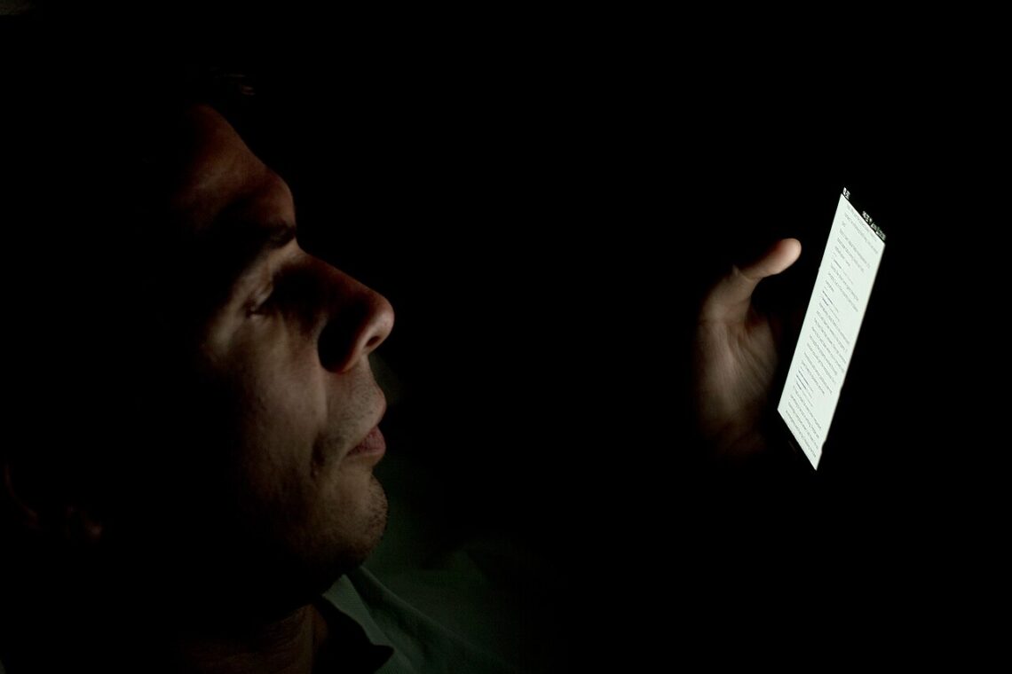 Digital Arrest Scam: How It Works and How to Stay Safe A person looking at a smartphone screen in a dark room