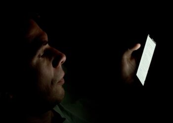 A person looking at a smartphone screen in a dark room