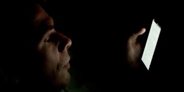 A person looking at a smartphone screen in a dark room