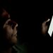 Digital Arrest Scam: How It Works and How to Stay Safe A person looking at a smartphone screen in a dark room