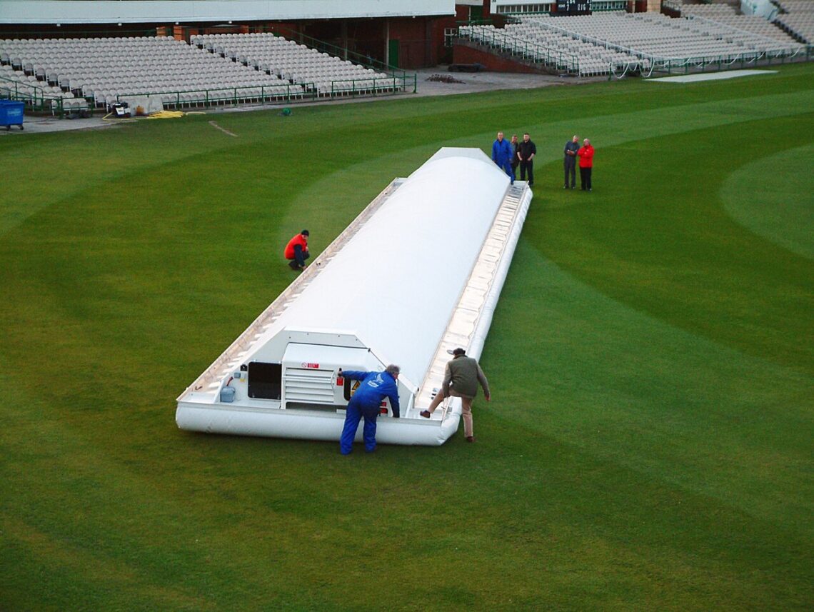 DLS Method in Cricket Explained: How Rain-Hit Targets Are Set Hover cover protecting the pitch at Old Trafford cricket ground during rain