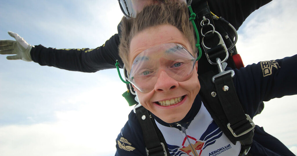 The World's Top 5 Locations For A Perfect Skydive In 2026 A tandem skydiver and instructor in freefall above the clouds